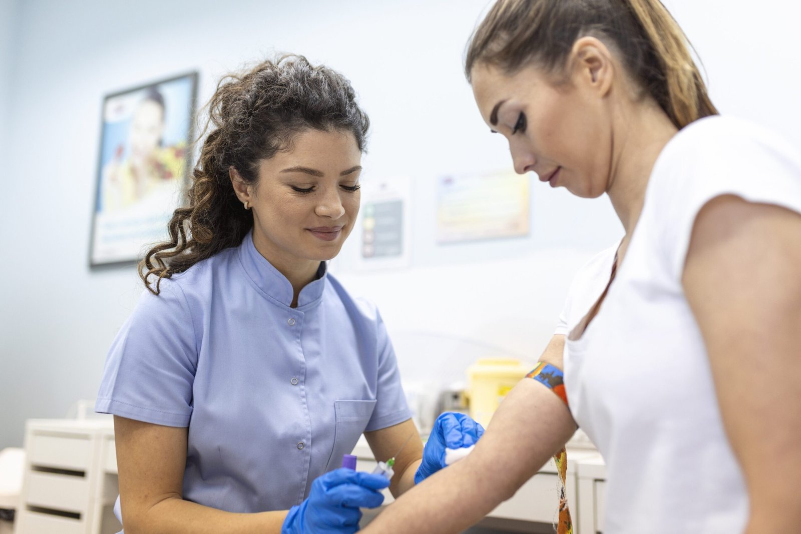 Profesional de salud con guantes realizando punción en el brazo de una paciente para aplicación de inyección o toma de muestra en consultorio.