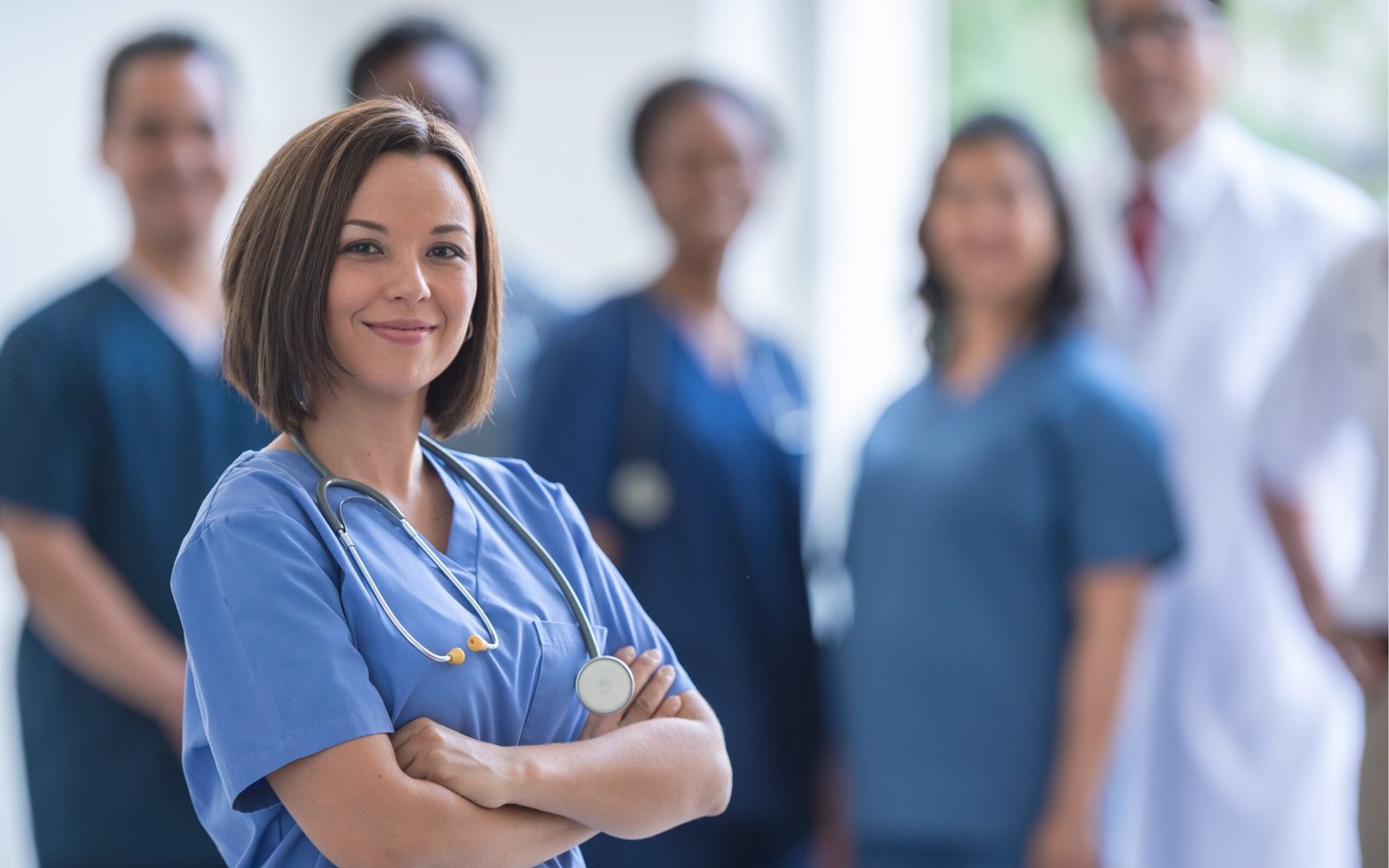 Profesional de salud con estetoscopio y equipo médico al fondo en un entorno clínico